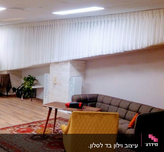 וילון לבן ארוך תלוי מהתקרה לאורך הקיר
